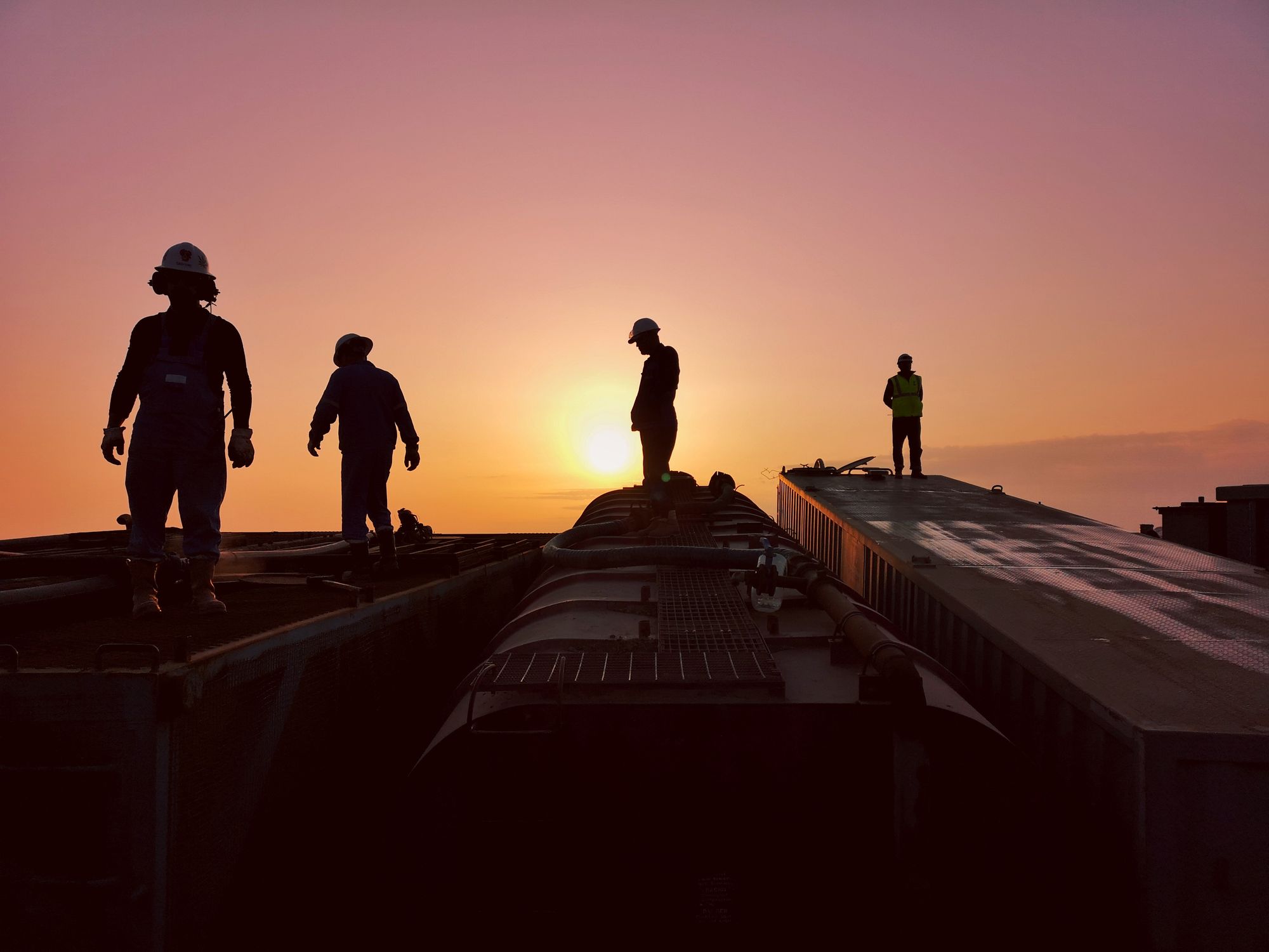 Techniciens sur une installation technique au coucher du soleil